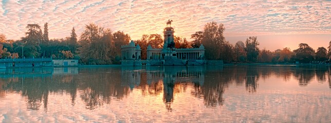 Panoramic view of the Retiro Park in Madrid with a sunrise and golden hour and a lake and building