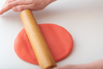 A woman makes homemade Valentine's Day cookies from shortcrust pastry in the form of red hearts.