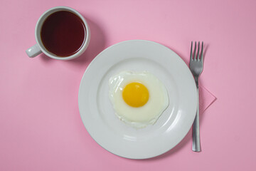 Scrambled eggs on a pink background. Fried eggs on a white plate. Delicious breakfast with a cup of coffee.