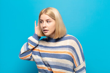 blonde woman looking serious and curious, listening, trying to hear a secret conversation or...