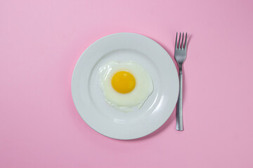Scrambled eggs on a pink background. Fried eggs on a white plate. Tasty breakfast.