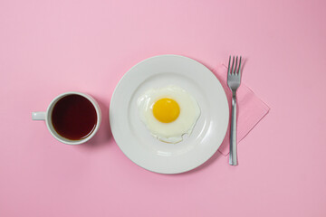 Scrambled eggs on a pink background. Fried eggs on a white plate. Delicious breakfast with a cup of coffee.