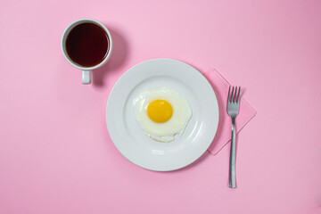 Scrambled eggs on a pink background. Fried eggs on a white plate. Delicious breakfast with a cup of coffee.