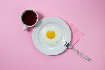 Scrambled eggs on a pink background. Fried eggs on a white plate. Delicious breakfast with a cup of coffee.