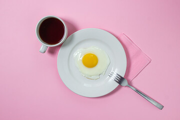 Scrambled eggs on a pink background. Fried eggs on a white plate. Delicious breakfast with a cup of coffee.