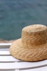 Straw hat on the deck chair by the water. Selective focus.