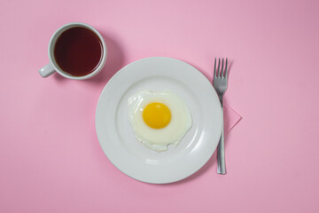 Scrambled eggs on a pink background. Fried eggs on a white plate. Delicious breakfast with a cup of coffee.