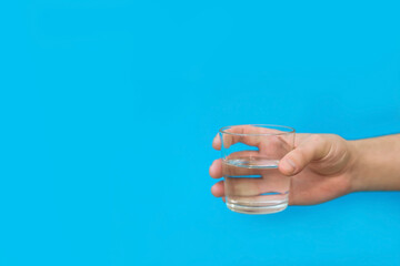 glass of clean drinking water on blue background copy space