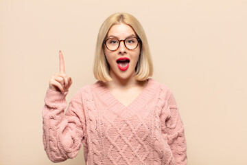 blonde woman feeling like a happy and excited genius after realizing an idea, cheerfully raising...