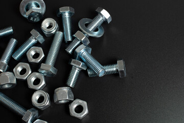 many metal bolts and nuts against black background