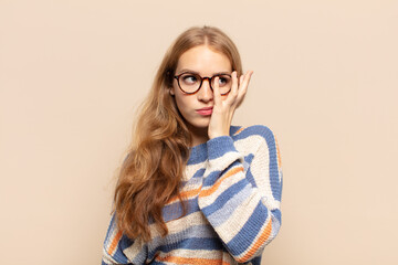 blonde woman feeling bored, frustrated and sleepy after a tiresome, dull and tedious task, holding...