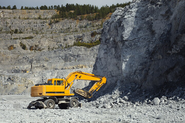 Excavator with hydraulic hammer in a limestone quarry.