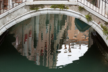 Reflections of Venitian houses under a typical pedestrian bridge, Venice, Italy