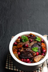 Braised beef with cranberries in clay bowl isolated on white