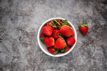 Fresh strawberries in a white bowl on dark background. vegan food. Top view with copy space. healthy food concept
