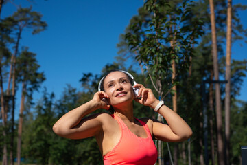 Portrait of a fit woman with headphones standing in a pine forest and looking away