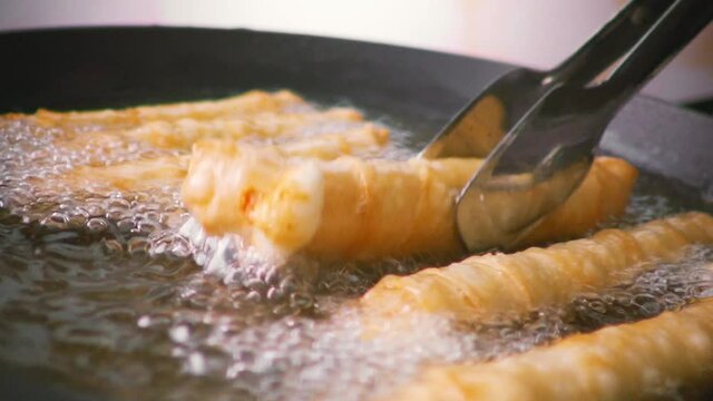 Preparation of the national Turkish dish sigara boregi. Rolls of dough fried in a frying pan in oil. Slow motion.