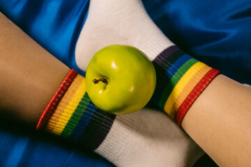 Human legs with rainbow socks and a green apple