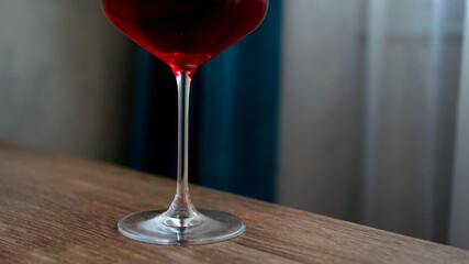 Long stem wine glass with red wine indoor blurred background