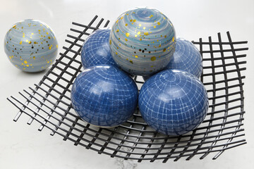 Blue glass orbs and a wire mesh bowl on a white background