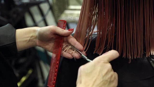 The hairdresser's hands with scissors cut and mill the hair in salon. Women's haircut and hairstyle. Close-up