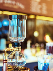 Close up to barista make coffee with Vacuum Pot Syphon Brewer.  Syphon (Siphon) coffee maker brews drink using two chambers where vapor pressure and vacuum produce coffee in cafe. Selective focus.