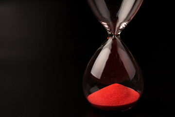 Crystal hourglass on black background as a concept of passing time for business term, urgency and...