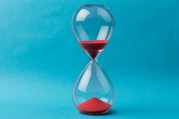Crystal hourglass on blue background as a concept of passing time for business term, urgency and...