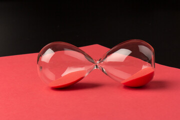 Crystal hourglass on black and red background as a concept of passing time for business term,...