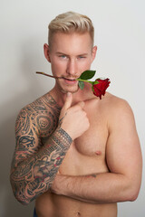 Male lover with a flower in the mouth / Handsome young man holding a red rose in his lips