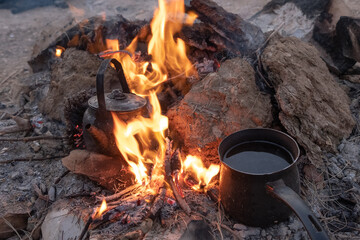 Sparkling bonfire with tea kettle and coffee pot in summer night background. Travel activity and vacation weekend.