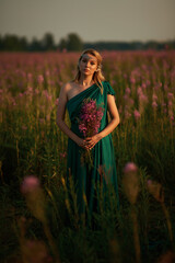 Young beautiful girl with a bouquet of flowers in her hands at sunset.