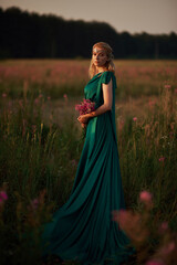 Young beautiful girl with a bouquet of flowers in her hands at sunset.