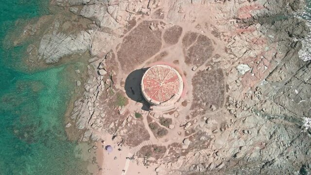 Torre di Bari, Bari Tower On Rocky Coast Near Sandy Beach With Umbrellas And Tourists On A Sunny Summer Day Nuoro, Sardinia, Italy. - aerial rotation shot