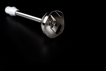 Electric hand blender nozzle with sharp blade isolated on the dark surface background.