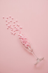 Girly pastel pink composition made of champaigne glass and confetti. Minimal trendy flat lay.