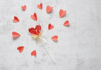 Valentine's day flat lay photography with red heart shape lollipop and paper cut hearts. Romantic greeting card background. 