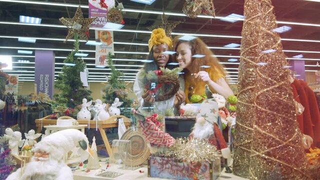 Happy girls check Christmas decorations in a store.