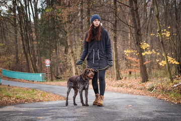 bond between the lady and her dog. Candid portrait of a young brunette and her Bohemian Wire-haired Pointing Griffon dog in the wild. Walk on the road. The intimate bond between animal and human