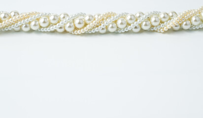 A necklace of beads of different sizes, white beige on a white background with a place to write the text.