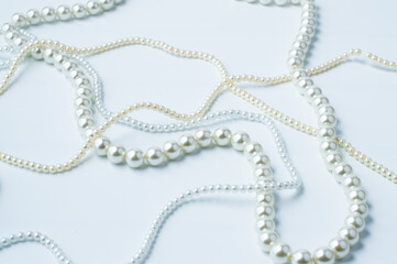 Blurred image of white beige necklaces with beads on a white background.
