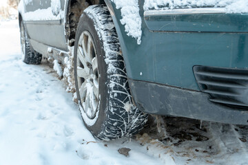 Parts of the car are covered with snow and ice after a snowfall. Wheel close-up in dirt and anti-icing reagents. Big frosts and a lot of snow in the city. Problems on winter slippery roads.