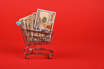 US dollar banknotes in shopping cart over red