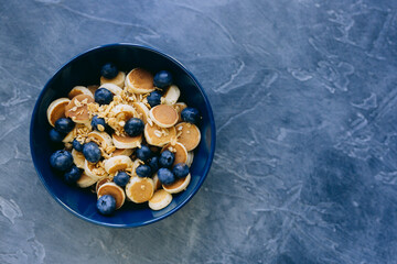 Close- up Mini Pancake cereal, mini pancakes in a dark blue bowl with sirup honey with blueberry