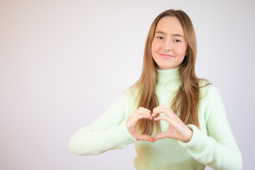 Young beautiful blonde woman wearing winter wool sweater over white isolated background smiling in love doing heart symbol shape with hands. Romantic concept.