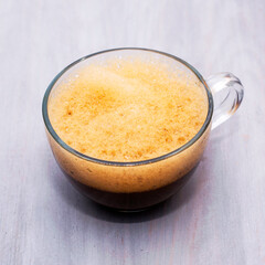 a glass cup of cappuccino coffee sits on the table