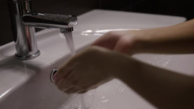 Woman picks up tap water and washes her face