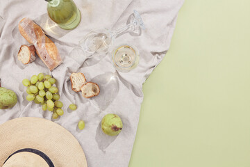 Creative picnic with wine and food flat lay. Minimal summer food background. Sunshine with shadow top view. Green pastel background