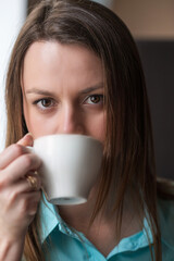 Young beautiful girl with brown hair drinks coffee in a cafe.