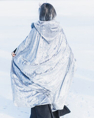 Fairy tale scene at arctic, woman in cold fantasy look, silver hair , cloak and dress at snowy day....